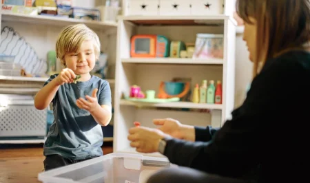 ABA therapist working one-on-one with a young autistic child during a play-based therapy session.